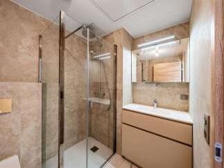 Experience modern luxury in this beautifully appointed bathroom, featuring a sleek glass-enclosed shower and a stylish vanity with ample storage.