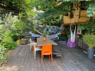 Enjoy outdoor living on this charming wooden deck, perfect for al fresco dining with a rustic wooden table and colorful chairs.