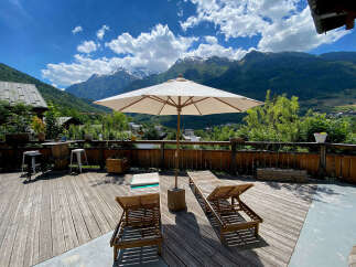 Enjoy breathtaking mountain views from this stunning deck, complete with comfortable lounge chairs and a large umbrella for shade.