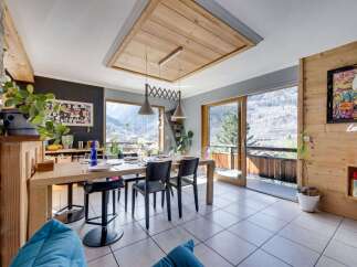 Experience breathtaking mountain views from this stunning dining area, featuring a large wooden table perfect for gatherings.