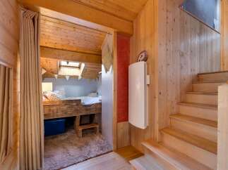 Discover this charming wooden cabin featuring a cozy loft bedroom accessible through a rustic curtain.