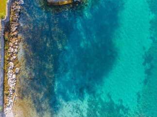 Experience waterfront living at its finest with this stunning aerial view of a property featuring crystal-clear turquoise waters perfect for swimming and water sports.