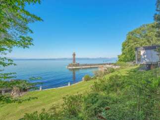 Experience breathtaking waterfront living with this stunning property, featuring a picturesque lighthouse and pier extending into the serene blue waters.