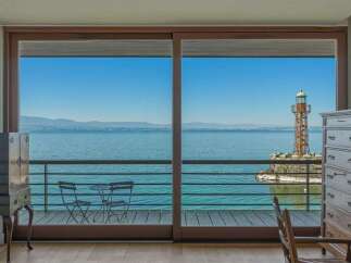 Experience breathtaking lake views from this stunning property, featuring a picturesque lighthouse and distant mountains.