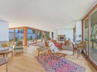 Experience luxurious living in this expansive great room, featuring a cozy fireplace and abundant natural light streaming through floor-to-ceiling windows.