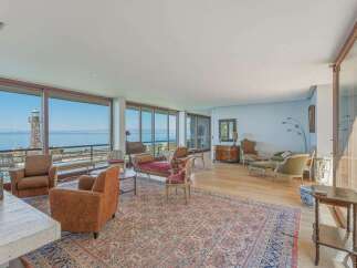 Experience breathtaking ocean views from this stunning living room, featuring expansive floor-to-ceiling windows that frame a picturesque lighthouse and coastline.