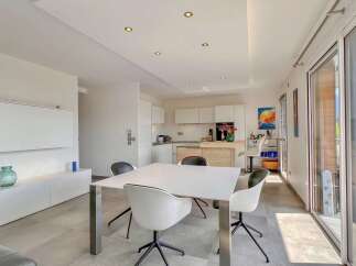 Experience modern living in this bright and airy apartment, featuring a sleek white dining table with contemporary chairs, perfect for intimate meals.