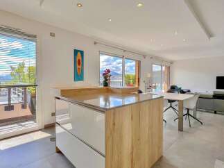 Experience modern living in this spacious open-plan apartment, featuring a sleek kitchen island and a bright, airy living area.