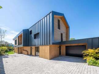 Discover modern living in this stunning architectural home, featuring a striking combination of vertical dark metal siding and warm natural wood accents.