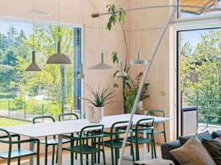Experience modern living in this bright dining area, featuring a sleek white table surrounded by stylish green chairs.