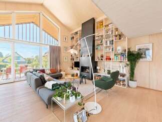 Experience modern living in this stunning open-concept living space, featuring a soaring vaulted ceiling with exposed wooden beams and expansive floor-to-ceiling windows that flood the room with natural light.