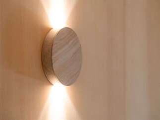 Illuminate your space with this modern, circular wall sconce featuring a natural wood finish.