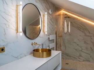 Experience modern luxury in this stunning bathroom featuring a sleek white vanity topped with a striking gold vessel sink and a large oval mirror.