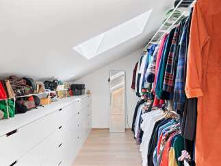 Discover ample storage solutions in this spacious walk-in closet, featuring a long row of white drawers and shelving units perfect for organizing clothing and accessories.