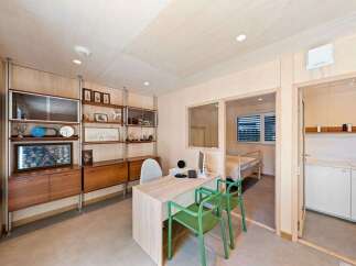 This modern office space features a sleek desk with green chairs, complemented by a wall of vintage-inspired shelving displaying various decorative items.