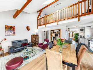 Experience spacious living in this open-concept home featuring a vaulted ceiling with exposed wooden beams and a charming loft overlooking the main living area.