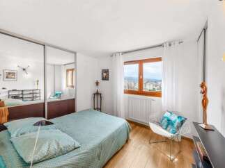 This charming bedroom features a spacious bed with light blue bedding, complemented by a large mirrored wardrobe offering ample storage.