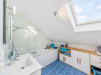 Discover this charming attic bathroom featuring a spacious bathtub and a modern sink, perfect for relaxation.
