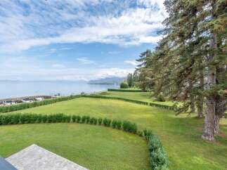Experience breathtaking lake views from this stunning property, featuring a meticulously manicured lawn and mature trees.