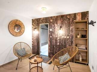 Step into a serene spa-like oasis featuring two stylish rattan chairs with decorative pillows, perfect for relaxation.