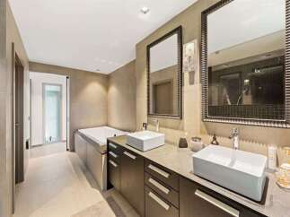Experience luxury in this modern bathroom featuring a deep soaking tub and a spacious vanity with dual vessel sinks.