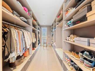 Step into this expansive walk-in closet, meticulously organized with custom shelving and ample hanging space for your wardrobe.