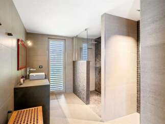 Experience modern luxury in this stunning bathroom featuring a sleek vanity with a vessel sink and a spacious walk-in shower enclosed by glass.