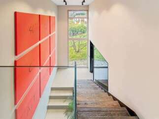 This modern home features a striking accent wall with vibrant red panels adorned with handwritten numbers, adding a unique artistic touch to the hallway.