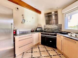 This charming kitchen features a spacious stainless steel refrigerator and a sleek black range with a modern hood.