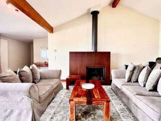 Experience modern living in this spacious living room featuring a striking fireplace with a dark wood surround and a sleek black chimney.