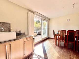 This spacious dining area seamlessly connects to a modern kitchen, featuring a large sink and ample counter space.