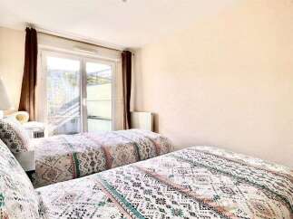 This charming bedroom features two comfortable twin beds, each adorned with a stylish, patterned comforter.