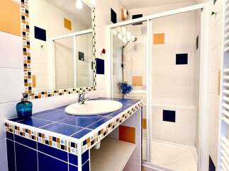 This charming bathroom features a vibrant blue tiled vanity with a modern sink and a decorative mosaic backsplash.