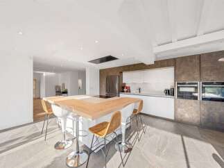 Experience modern luxury in this stunning open-concept kitchen, featuring a sleek white cabinetry system and a striking metallic backsplash.