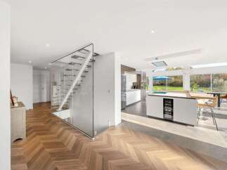 Experience modern luxury in this stunning home featuring a sleek glass-enclosed staircase and an open-concept living space.