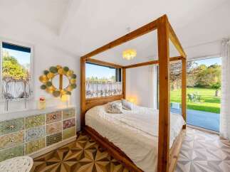 Experience serene living in this charming bedroom featuring a beautiful four-poster bed and a unique dresser adorned with colorful, patterned drawers.