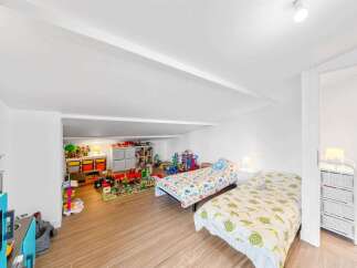 This charming attic bedroom is a dream come true for children, featuring two cozy beds perfect for sleepovers and a dedicated play area.