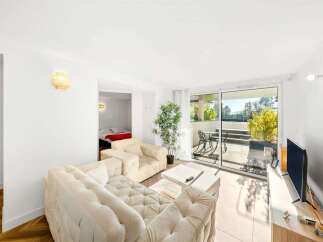 Experience modern living in this bright and airy apartment, featuring a spacious living area with plush seating and a large TV.