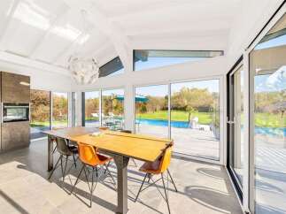 Experience modern living in this stunning home featuring a spacious dining area with a large wooden table and vibrant orange chairs.