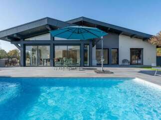 Experience luxurious outdoor living with this stunning modern home featuring a sparkling swimming pool and expansive patio area.