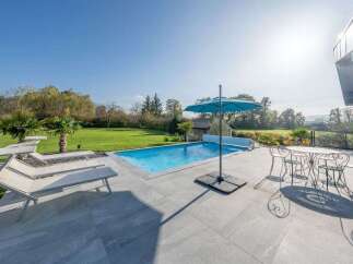 Enjoy luxurious outdoor living with this stunning property featuring a sparkling swimming pool and ample lounge seating.