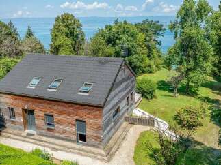 Discover this charming wooden house nestled amidst lush greenery, offering serene lake views.