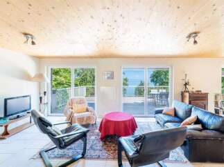 Experience breathtaking lake views from this stunning living room, featuring a cozy seating area with a plush sofa and armchairs.