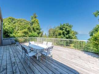 Enjoy breathtaking water views from this expansive wooden deck, perfect for outdoor dining and relaxation.