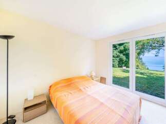 Experience serene living with this charming bedroom featuring a cozy bed adorned with a vibrant orange and pink striped blanket.