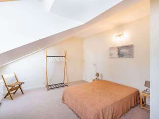 Discover this charming bedroom featuring a comfortable bed with a warm, textured throw.