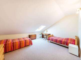 Discover this charming attic bedroom featuring two cozy single beds, perfect for guests or a shared space.