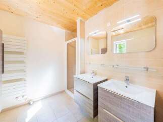 This modern bathroom features dual vanities with integrated sinks, providing ample space for couples.