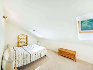 Discover this charming attic bedroom, featuring a comfortable single bed adorned with a patterned duvet.