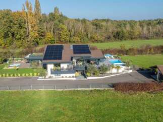 Experience modern luxury in this stunning property featuring a sleek contemporary home with a green roof and solar panels.